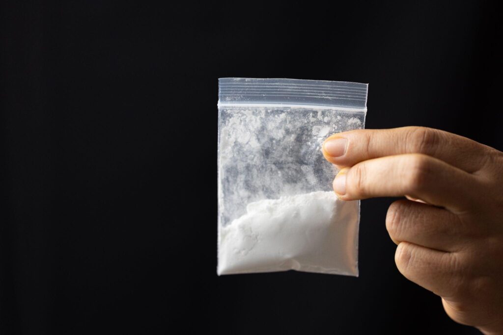 hand holding bag of heroin on black background